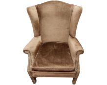 A wingback armchair in studded brown upholstery.