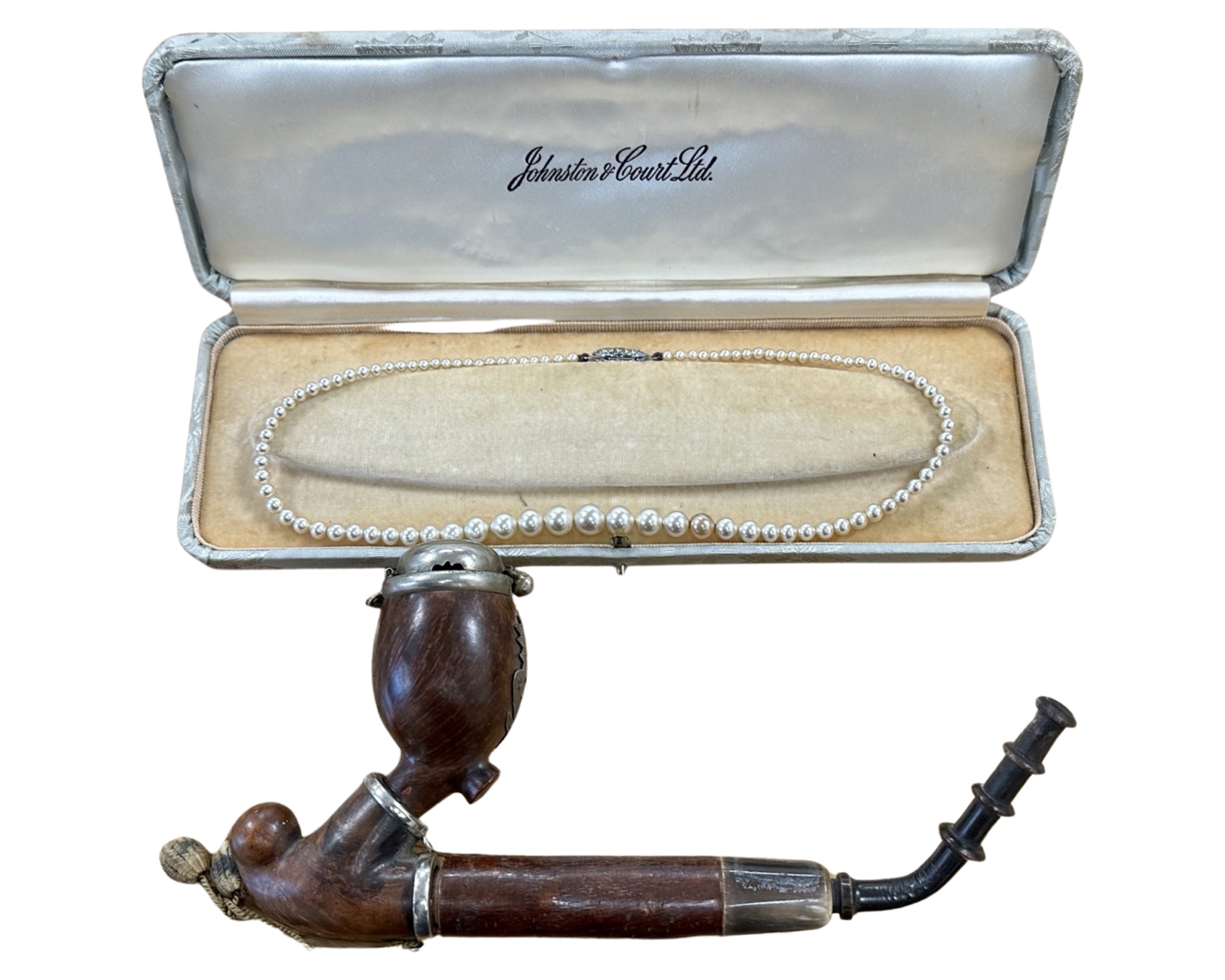 A single strand costume pearl necklace and an antique pipe.