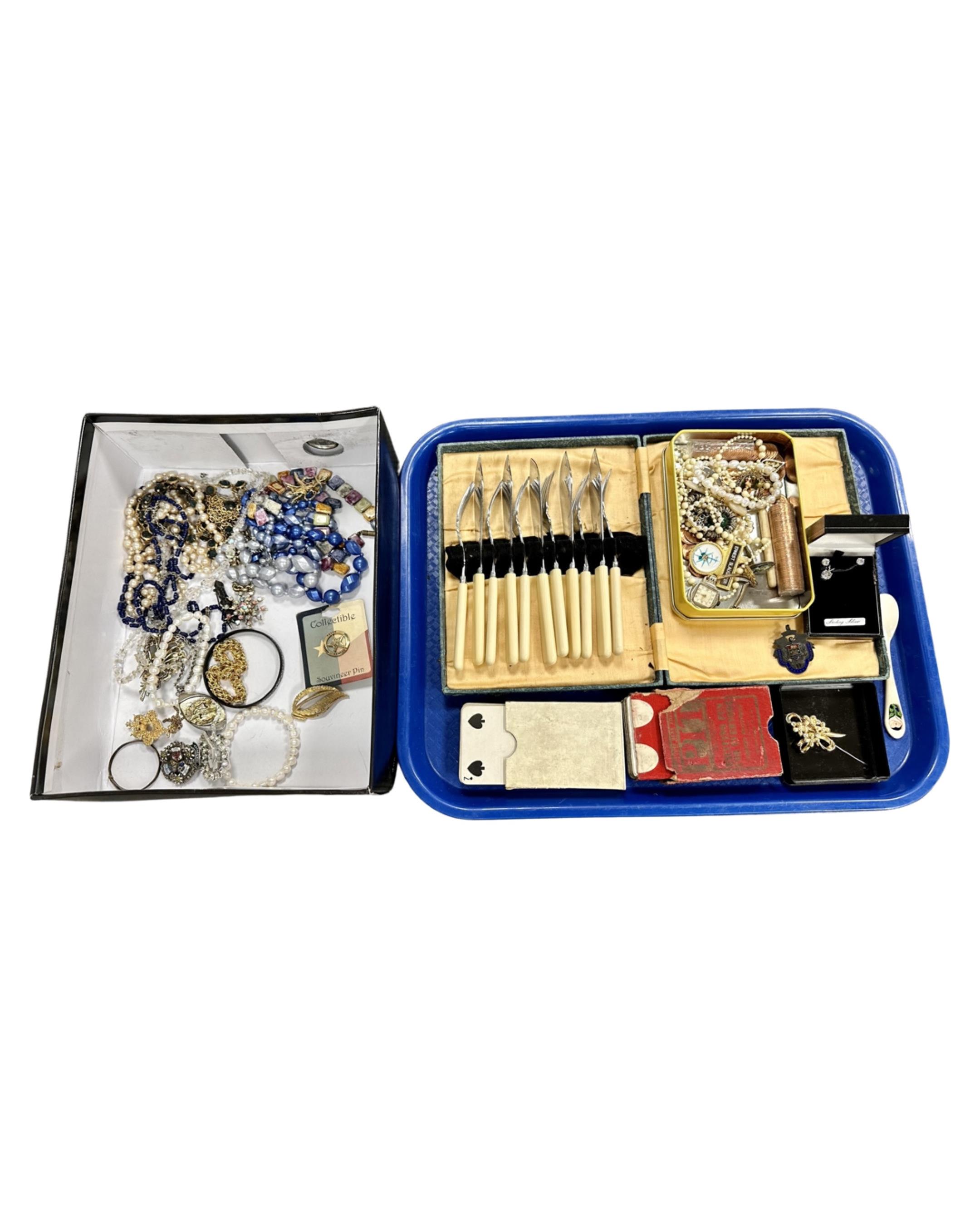 A tray containing costume jewellery, playing cards, cased cutlery,