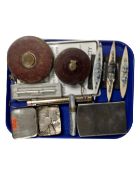 Two vintage leather cased tape measures, a tin containing trophy badges,