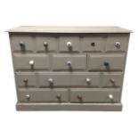 A painted pine thirteen drawer block chest with odd handles