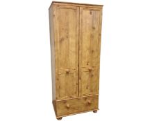 An Alston Furniture double door wardrobe fitted with a drawer, in a rustic pine finish.