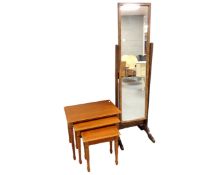 A nest of three tables in a teak finish together with a cheval mirror.