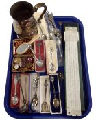 A tray containing a plated tankard, a collection of crested spoons, enamelled badges,