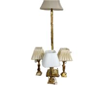 A brass standard lamp together with three brass table lamps, all with shades.