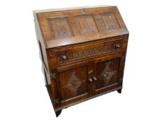 A Jaycee Furniture oak linen fold bureau fitted with a drawer and cupboards beneath.