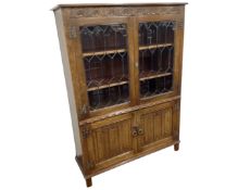 A Jaycee Furniture oak linen fold double door leaded glass bookcase.