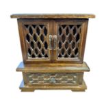 A wooden musical jewellery box modelled as a fretwork cabinet with internal drawers,