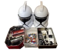 A box containing two Star Wars clone trooper helmets, plastic figures, toy train and car parts.