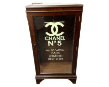 An inlaid mahogany display cabinet baring Chanel advertising.