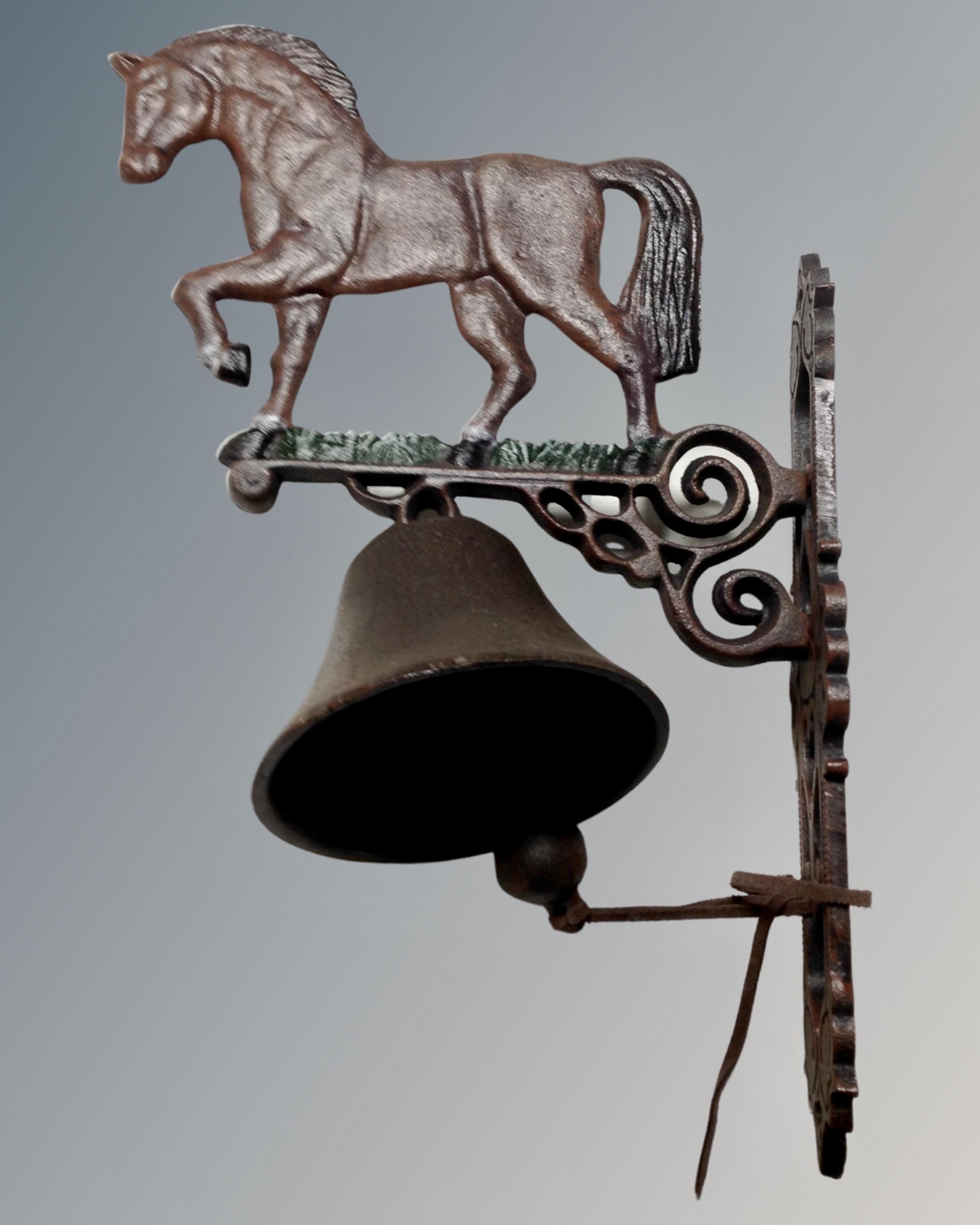 A cast iron horse wall bracket with bell.