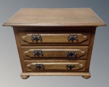 A continental oak three drawer chest on bun feet.