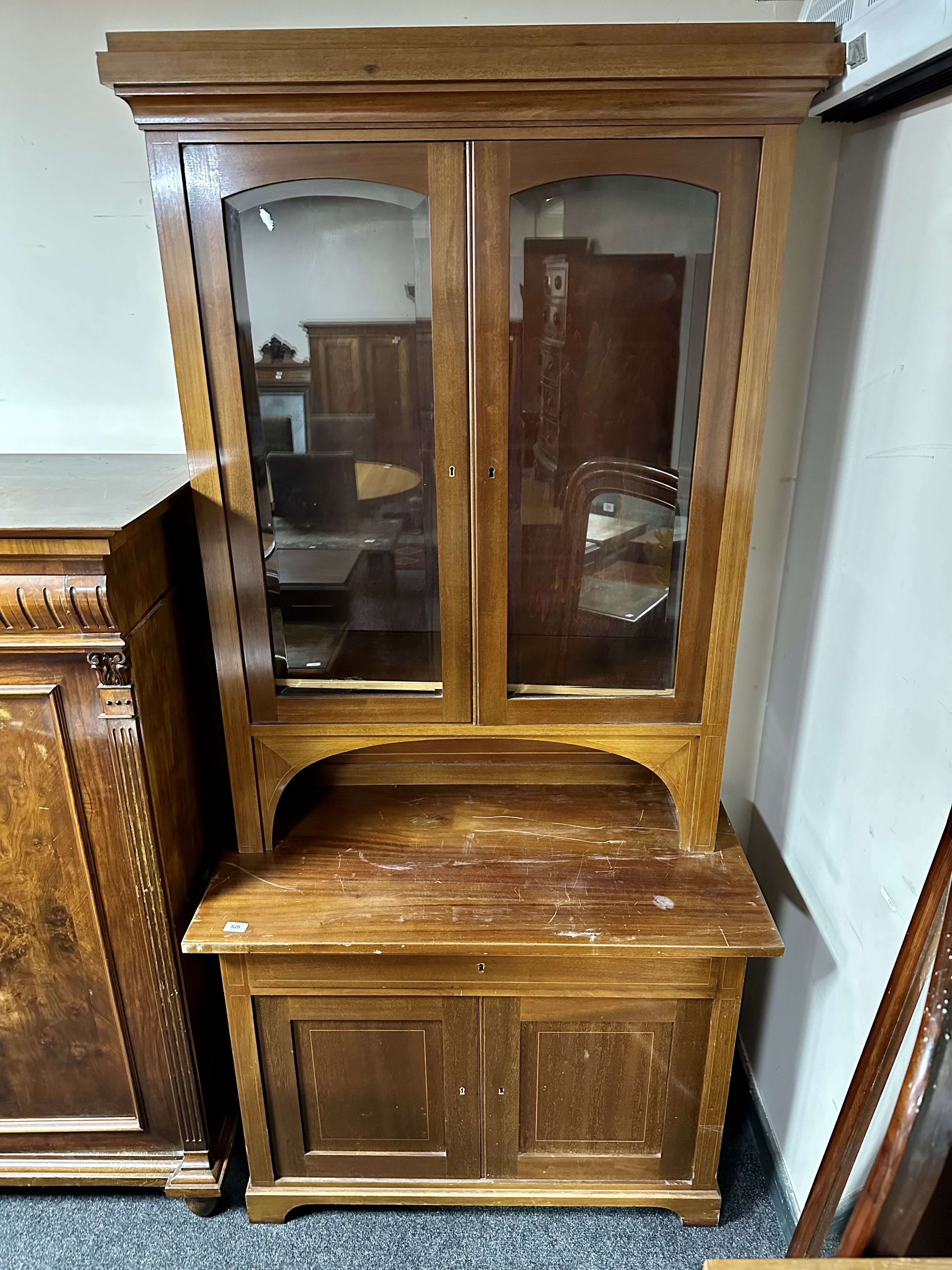 An early 20th century continental inlaid mahogany glazed door bookcase fitted with cupboards and