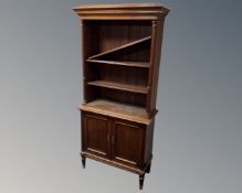 A mahogany open bookcase on raised legs fitted with cupboards beneath.