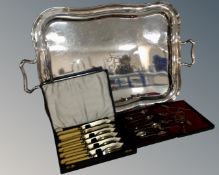 A silver plated twin handled serving tray together with a cased set of teaspoons,