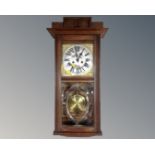 An Edwardian oak cased eight day wall clock with pendulum and key.
