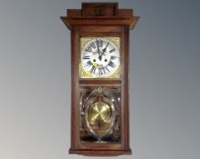 An Edwardian oak cased eight day wall clock with pendulum and key.