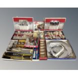 A vintage luggage case containing boxed cutlery including serving spoons, tea spoons, carving sets,