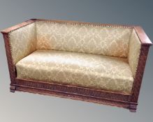 A continental carved oak hall settee upholstered in gold brocade fabric.