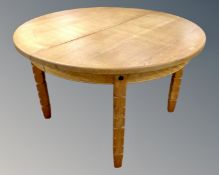 A Scandinavian blond oak circular extending dining table.