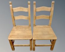 A pair of contemporary pine ladder back dining chairs.