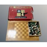 A wooden chessboard together with a box containing a quantity of assorted chess pieces and a