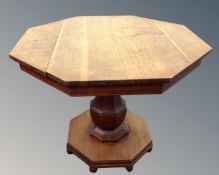 A 20th century octagonal oak pedestal occasional table.