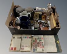A box containing a decanter with silver collar, badges, hip flasks, stamp albums, whiskey jugs,