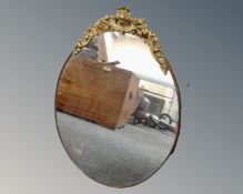 An oval frameless bevel edged mirror with gilt metal mount, height 62 cm width 46 cm.