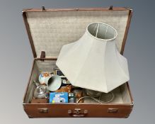 A vintage luggage case containing cameras, a plated teapot, china dog figures,