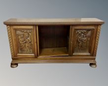 An early 20th century heavily carved oak double door cabinet fitted with central bookcase on bun