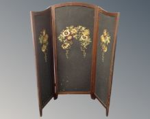 A mahogany three way folding screen with needlework decoration.