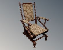 A 20th century bobbin turned rocking chair upholstered in tapestry fabric.