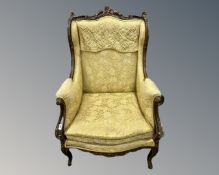 A French Louis XV style giltwood armchair upholstered in a gold brocade fabric.