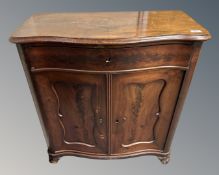 A 19th century mahogany serpentine fronted double door cabinet fitted with a drawer.