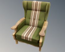 A 20th century oak armchair in green striped upholstery