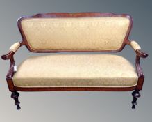 A continental mahogany and walnut framed salon settee upholstered in a gold brocade fabric.