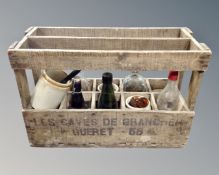A vintage French wooden caddy containing vintage glass bottles and jars.