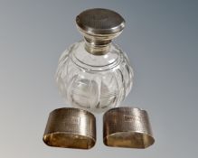 A cut glass silver lidded perfume bottle together with two further silver napkin rings