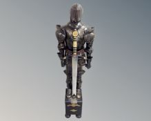 A miniature suit of armour with sword on wooden stand,