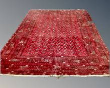 An Afghan Bokhara fringed carpet on red ground,