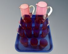 Two antique graduated cranberry glass jugs and a set of eleven beakers