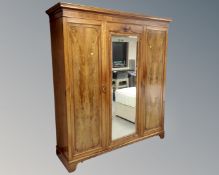 A late Victorian walnut triple door wardrobe with central mirrored panel door,