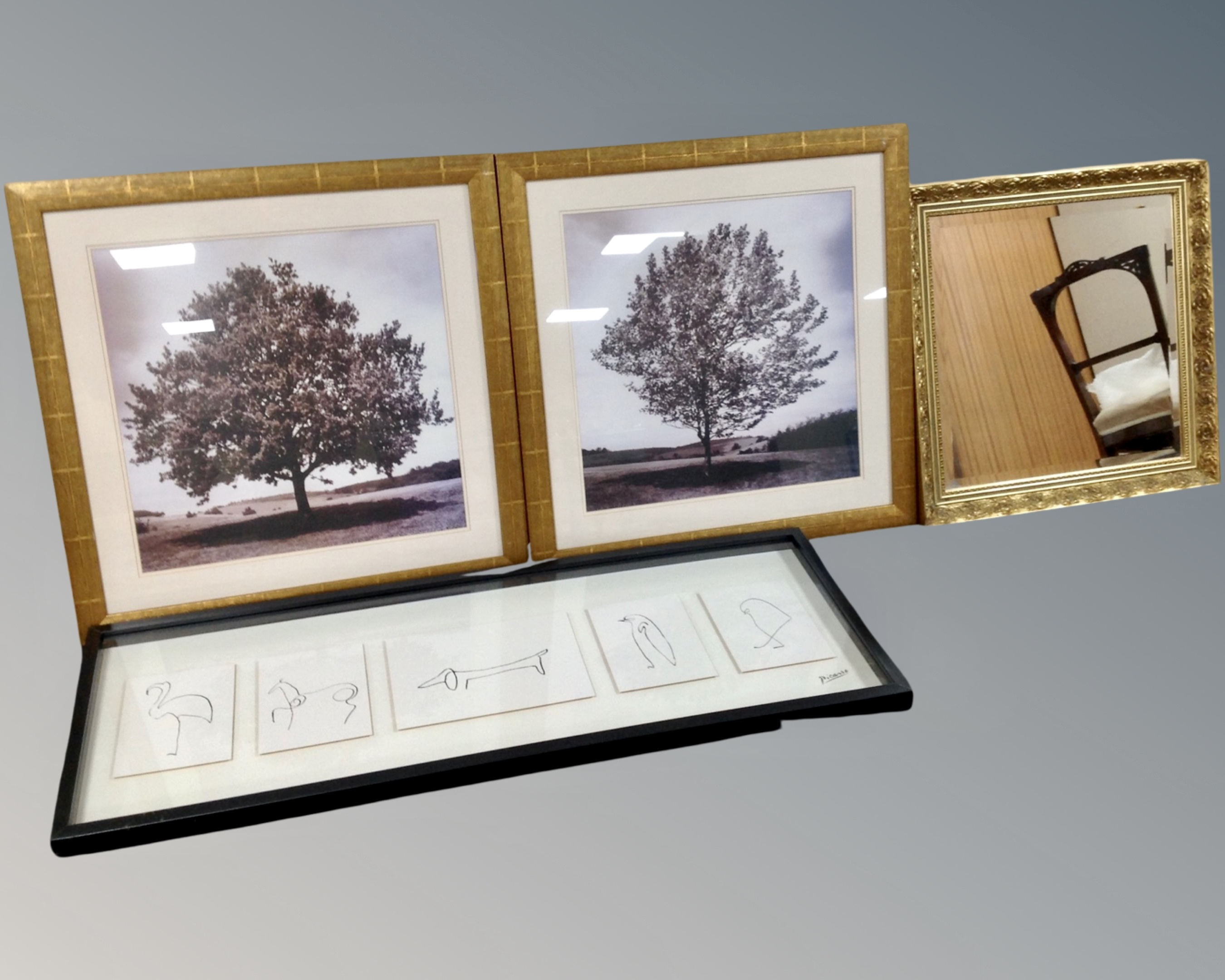 A gilt framed bevelled mirror together with two monochrome photographs depicting trees and a