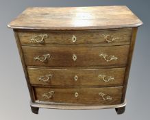 A 19th century oak bow fronted four drawer chest with gilt metal handles.