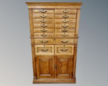 A late Victorian oak sixteen-drawer filing chest fitted with brass drop handles and cupboards