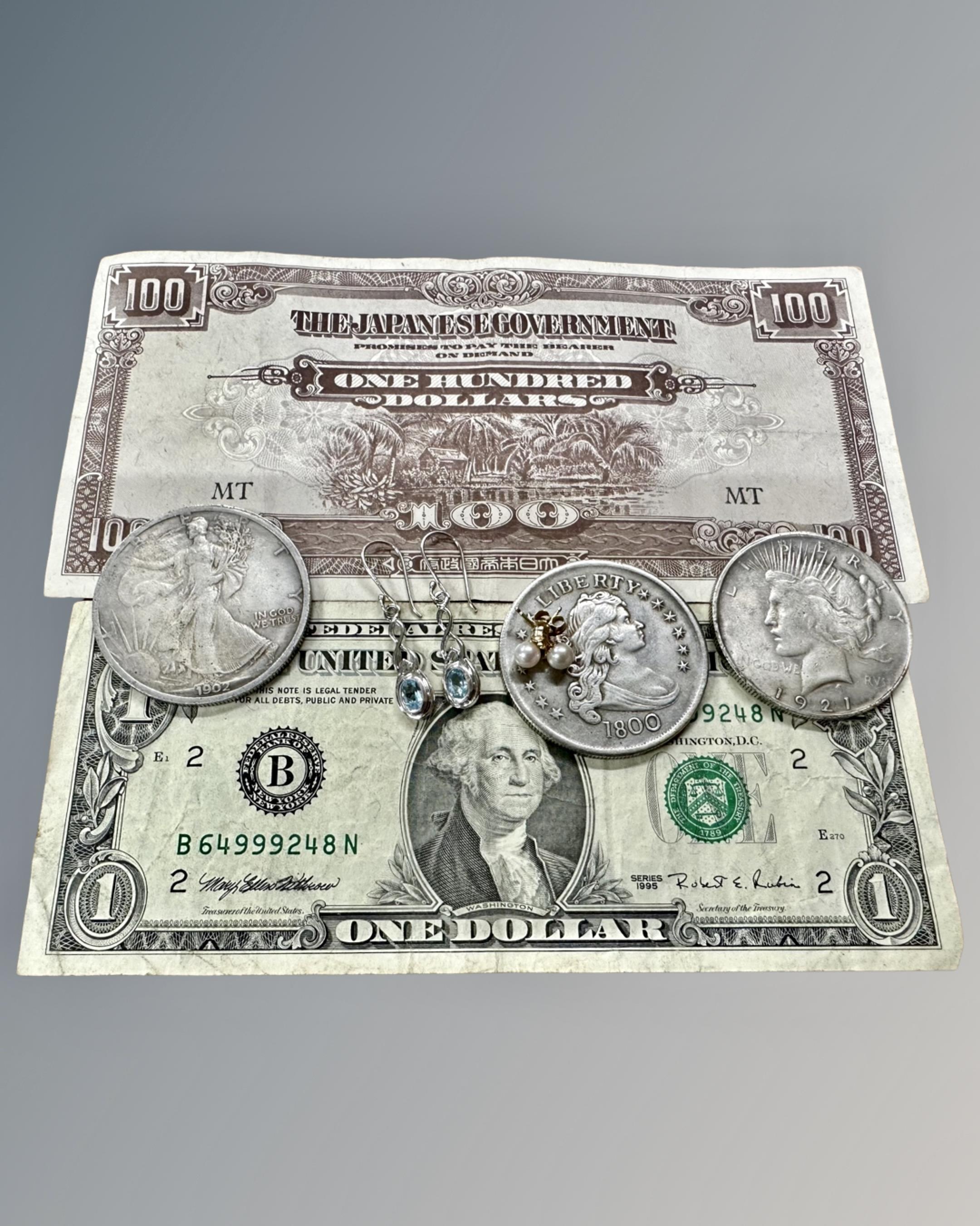 Three replica American silver dollars, a $1 bill, Japanese $100 bill,