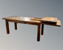 An oak farmhouse refectory dining table fitted with a drawer, with two extension leaves.