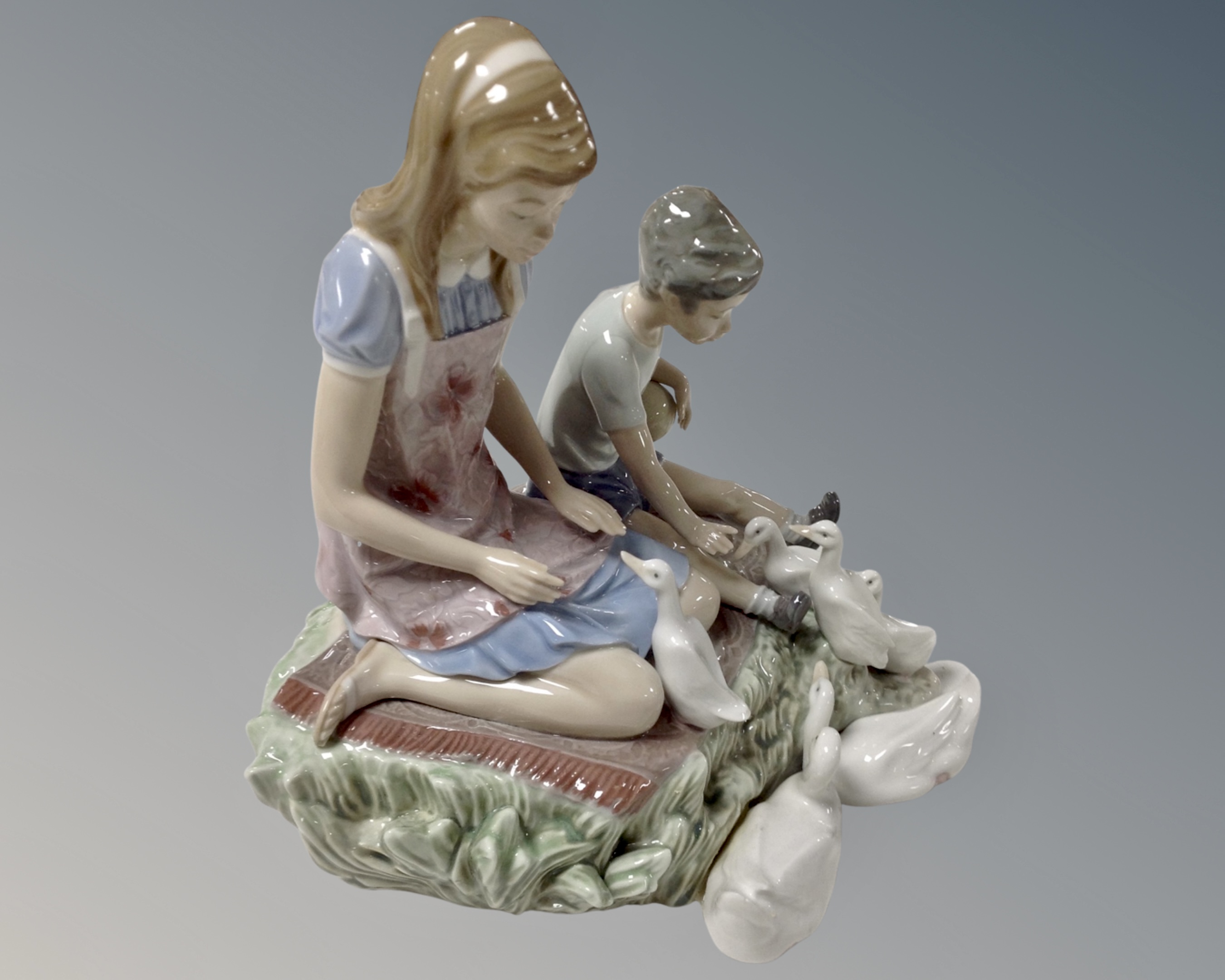 A Lladro figure group of a girl and boy feeding ducks.