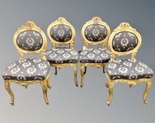 A set of four gilded Baroque dining chairs.